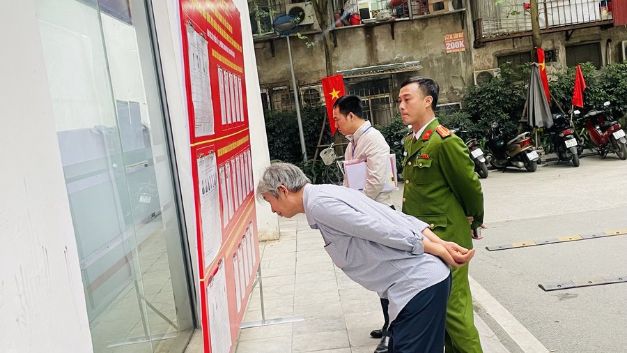 Cử tri tại khu vực bỏ phiếu số 18, phường Thanh Xuân nghiên cứu danh sách niêm yết trong khu vực bỏ phiếu